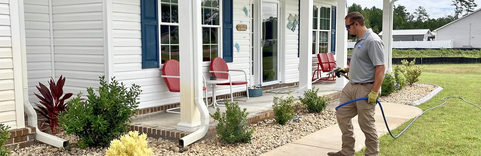 Tech spraying exterior of home, pest control